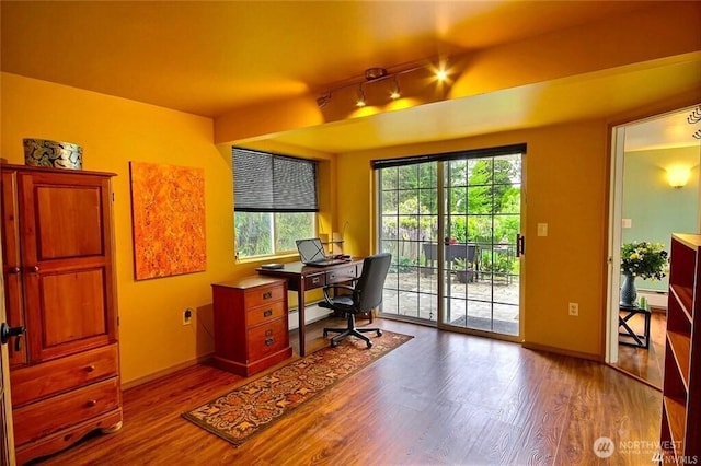 home office with baseboards, baseboard heating, wood finished floors, and track lighting