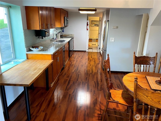 kitchen with a sink, stainless steel appliances, brown cabinets, and dark wood-style floors