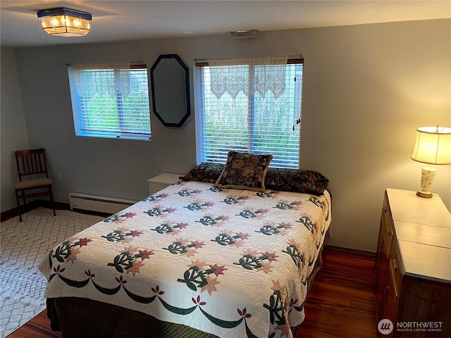 bedroom featuring baseboard heating, baseboards, and wood finished floors