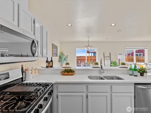 kitchen with a sink, a notable chandelier, appliances with stainless steel finishes, and light countertops