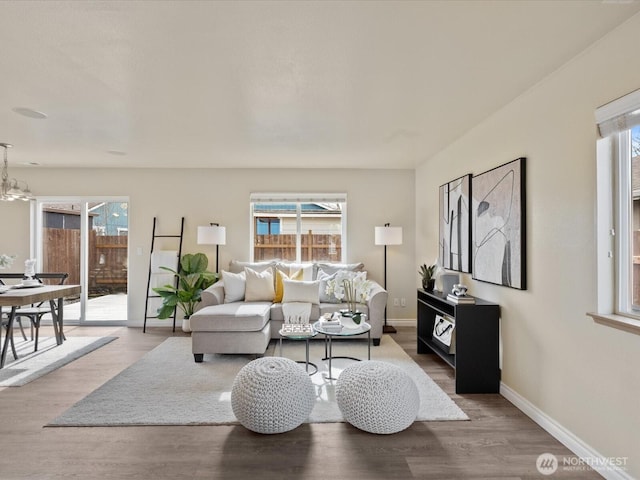 living area featuring baseboards, a notable chandelier, and wood finished floors