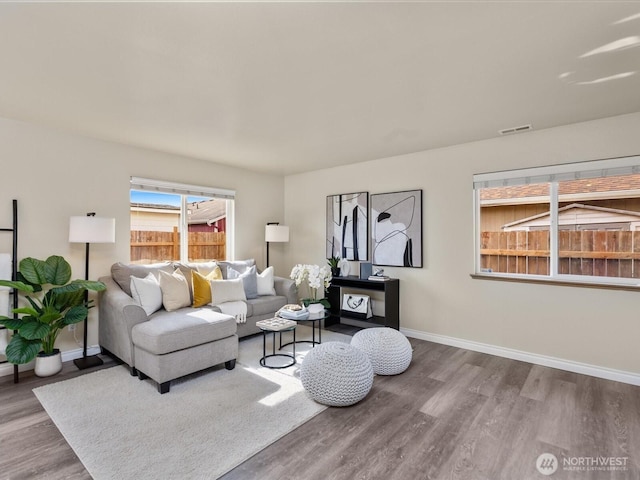 living room with visible vents, baseboards, and wood finished floors