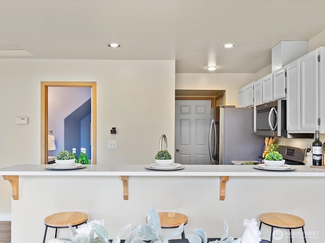 kitchen featuring a breakfast bar, a peninsula, stainless steel appliances, and light countertops