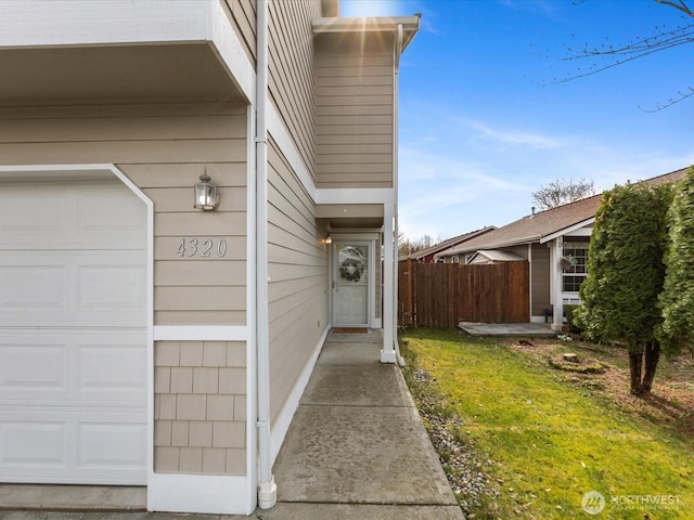 doorway to property featuring a garage and fence