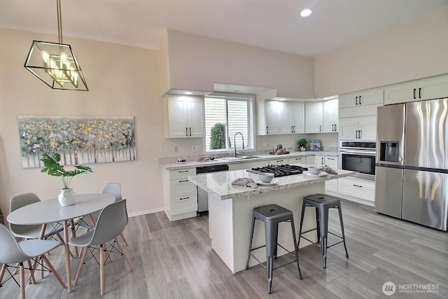 kitchen featuring light wood-type flooring, a sink, a center island, stainless steel appliances, and a breakfast bar area