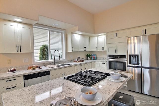 kitchen with a sink, light stone counters, white cabinetry, stainless steel appliances, and a breakfast bar area