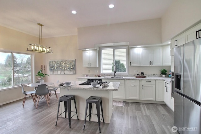 kitchen featuring a notable chandelier, a sink, a center island, white cabinetry, and stainless steel appliances