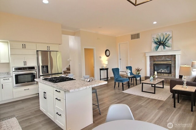 kitchen with light wood finished floors, visible vents, a kitchen bar, stainless steel appliances, and white cabinetry