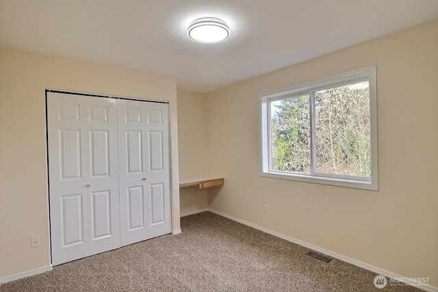 unfurnished bedroom with carpet flooring, baseboards, visible vents, and a closet