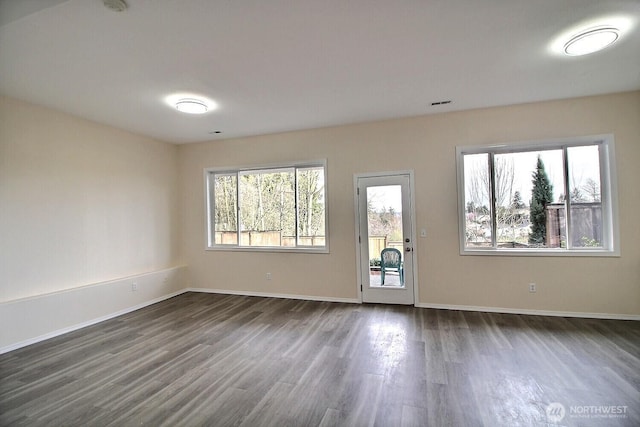 spare room featuring dark wood finished floors and baseboards