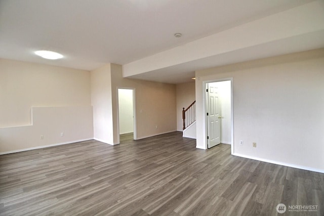 spare room featuring stairs, baseboards, and wood finished floors