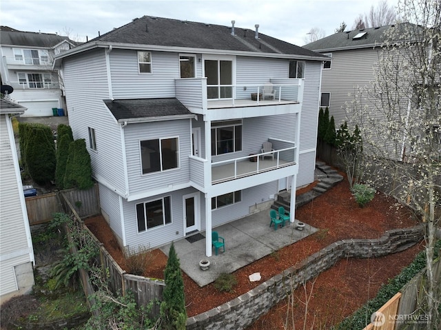 rear view of house featuring a patio, a balcony, roof with shingles, and a fenced backyard