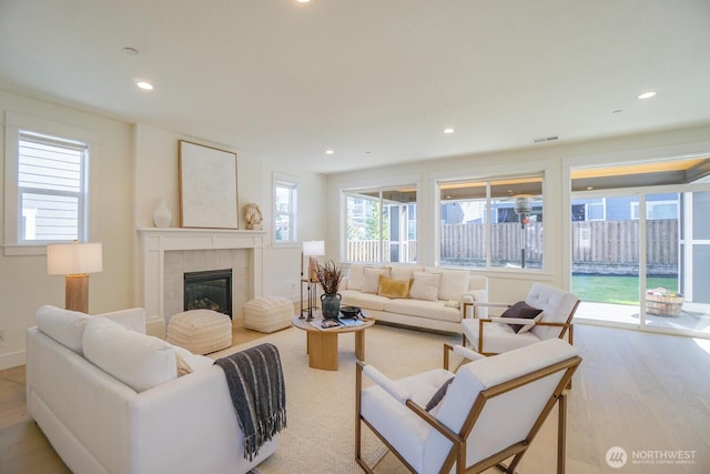 living area featuring visible vents, recessed lighting, a fireplace, and wood finished floors