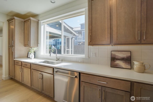 kitchen with a sink, tasteful backsplash, stainless steel dishwasher, and light wood-style flooring