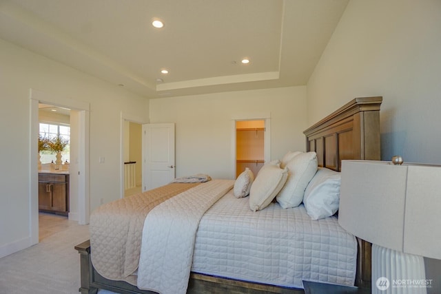 bedroom featuring a walk in closet, baseboards, a tray ceiling, recessed lighting, and ensuite bathroom