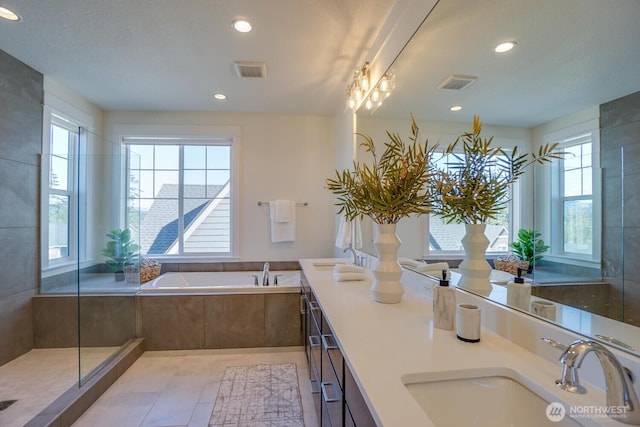 bathroom featuring tile patterned floors, a healthy amount of sunlight, visible vents, and a sink