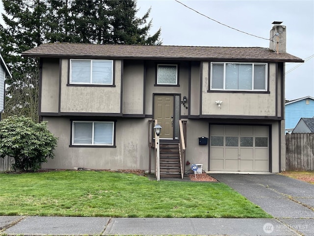 bi-level home featuring a front lawn, fence, a chimney, driveway, and an attached garage