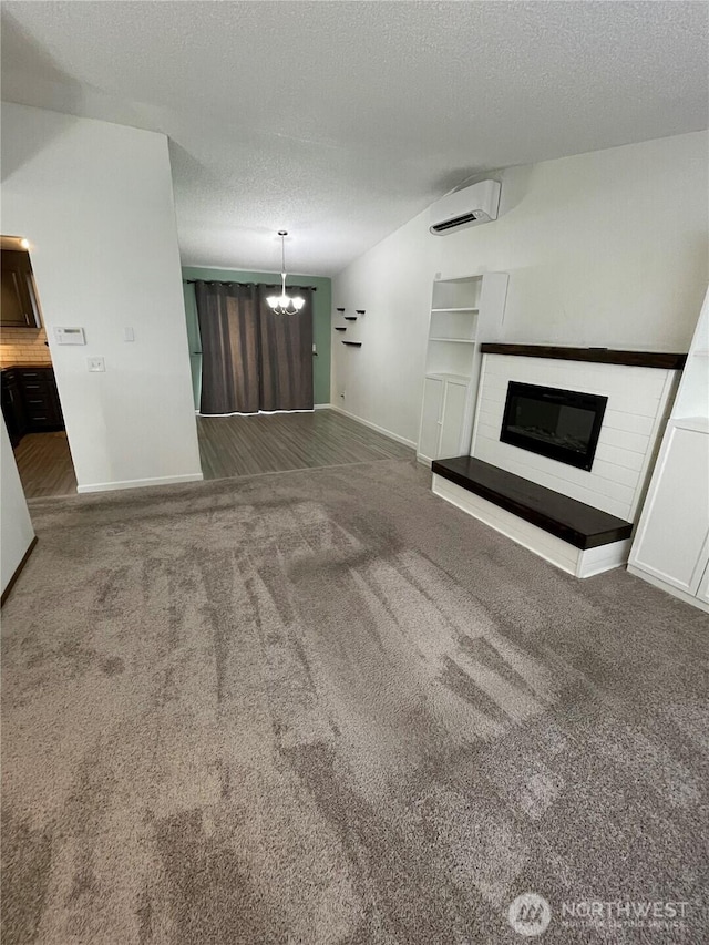 unfurnished living room featuring a glass covered fireplace, a textured ceiling, and carpet floors