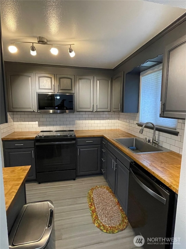 kitchen with dishwashing machine, a sink, black range with electric stovetop, stainless steel microwave, and butcher block counters