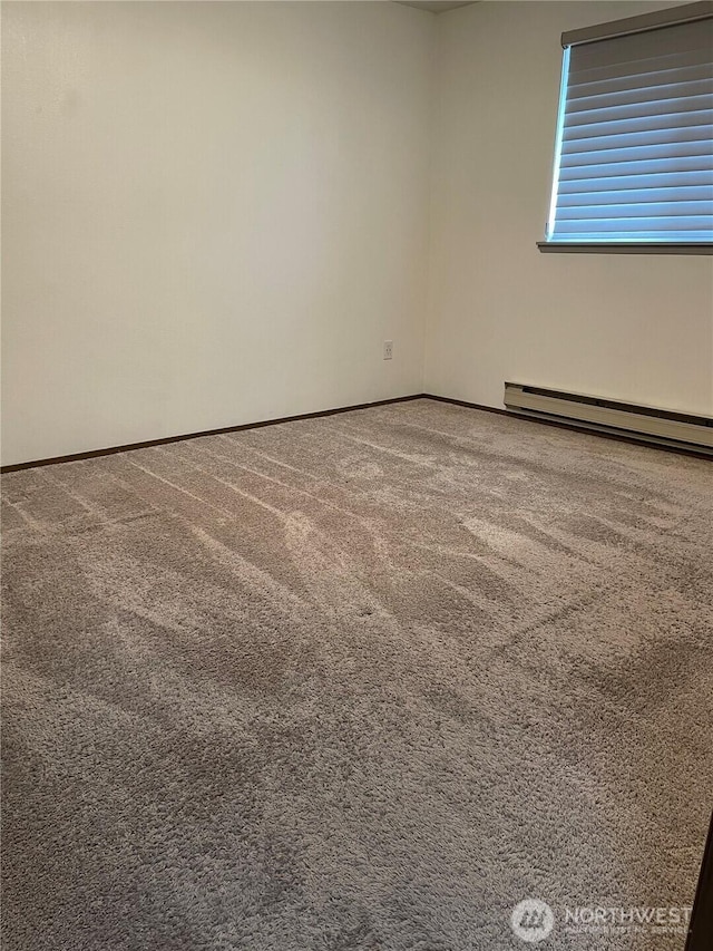 carpeted empty room featuring a baseboard heating unit and baseboards