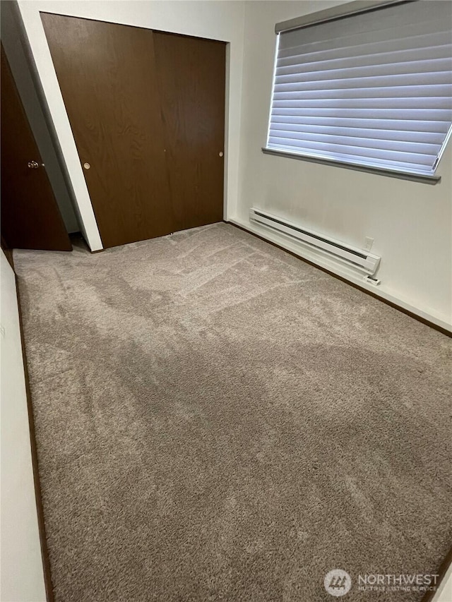 unfurnished bedroom featuring a closet, a baseboard heating unit, and carpet