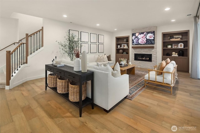 living area with recessed lighting, stairway, built in shelves, and light wood finished floors