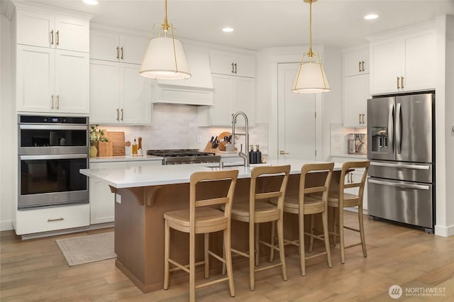 kitchen with tasteful backsplash, light wood-style flooring, appliances with stainless steel finishes, and light countertops