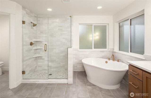 full bathroom featuring vanity, a soaking tub, recessed lighting, a shower stall, and toilet