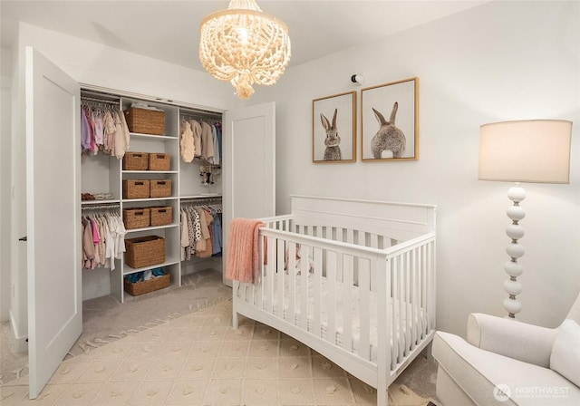 bedroom with a crib, an inviting chandelier, and a closet