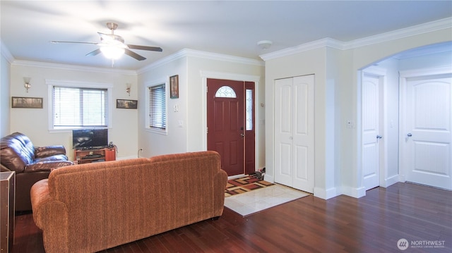 living room featuring baseboards, ornamental molding, wood finished floors, arched walkways, and a ceiling fan