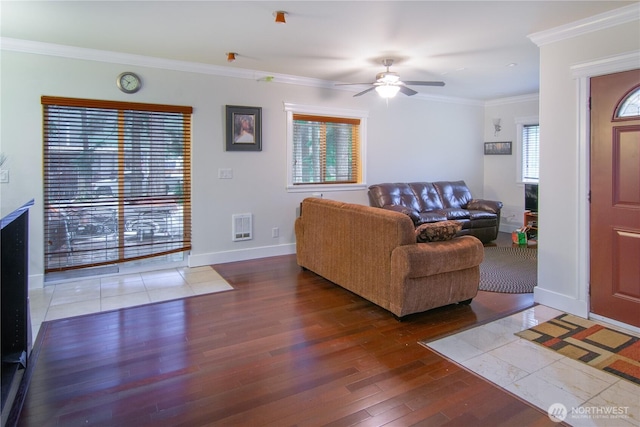 living area with crown molding, baseboards, ceiling fan, wood finished floors, and heating unit