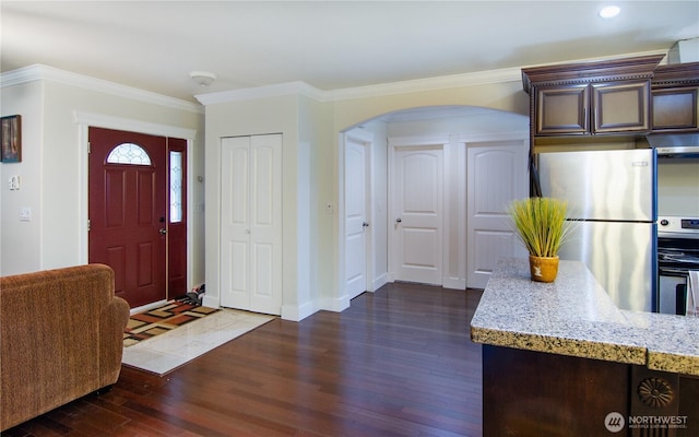 foyer entrance with baseboards, arched walkways, dark wood finished floors, and ornamental molding