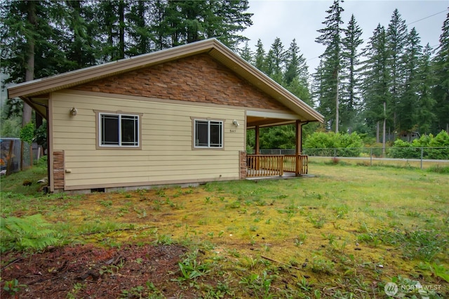 rear view of property featuring a lawn and fence