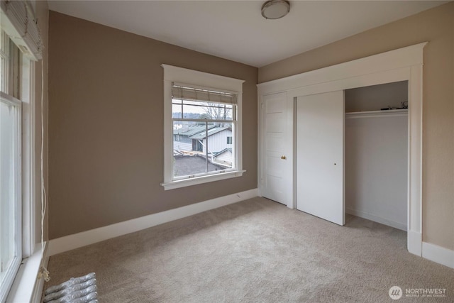 unfurnished bedroom with a closet, baseboards, and light colored carpet