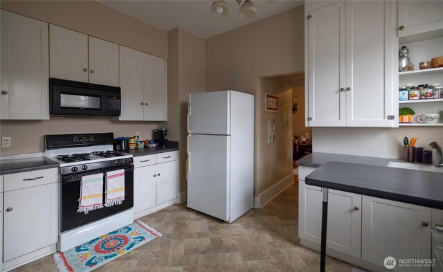 kitchen with range with gas stovetop, freestanding refrigerator, dark countertops, and black microwave