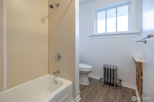 bathroom featuring vanity, radiator, wood finished floors, shower / washtub combination, and toilet