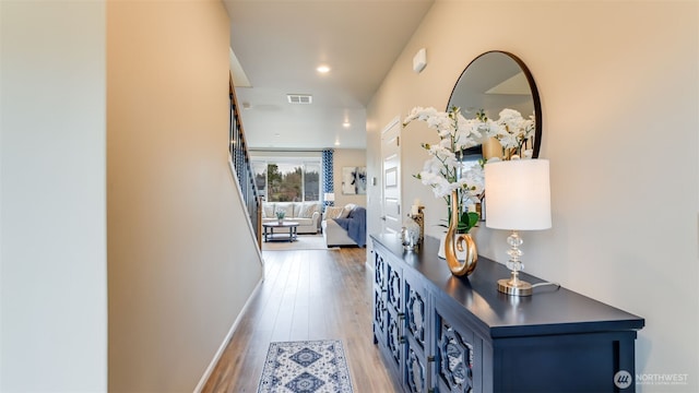 hall with visible vents, baseboards, and light wood-style floors