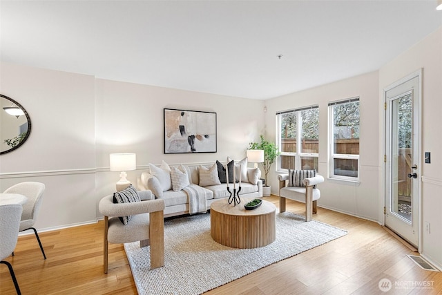 living room featuring light wood-style floors, visible vents, and baseboards