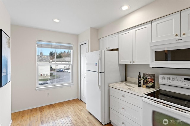 kitchen with light wood finished floors, recessed lighting, white appliances, and white cabinetry