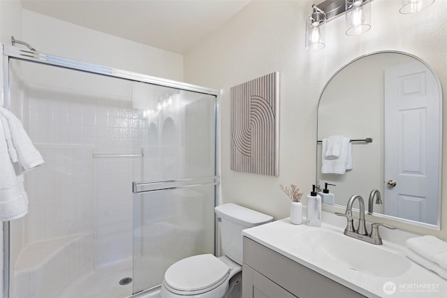 bathroom featuring toilet, a stall shower, and vanity