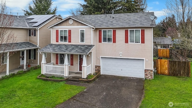 view of front of home with driveway, a front lawn, fence, covered porch, and an attached garage