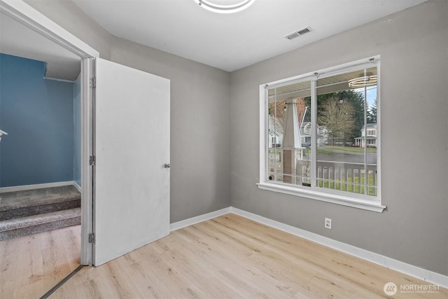 unfurnished room with wood finished floors, visible vents, and baseboards