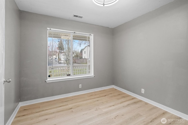 spare room featuring visible vents, baseboards, and wood finished floors