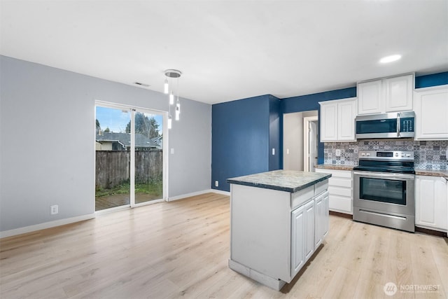 kitchen with decorative backsplash, appliances with stainless steel finishes, white cabinetry, and light wood-style floors