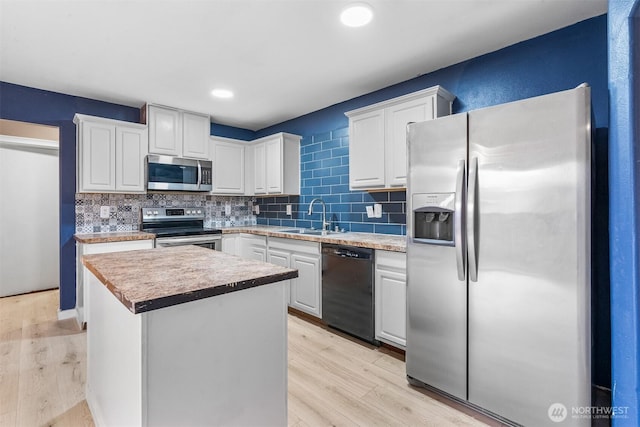 kitchen with light wood-style flooring, a sink, appliances with stainless steel finishes, white cabinetry, and backsplash