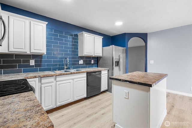 kitchen featuring arched walkways, dishwasher, light wood-style floors, and a sink