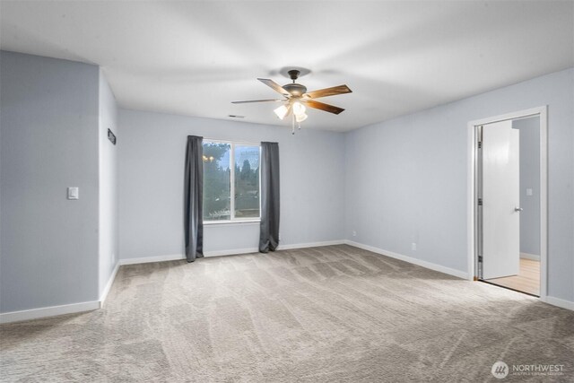 empty room with carpet flooring, ceiling fan, visible vents, and baseboards