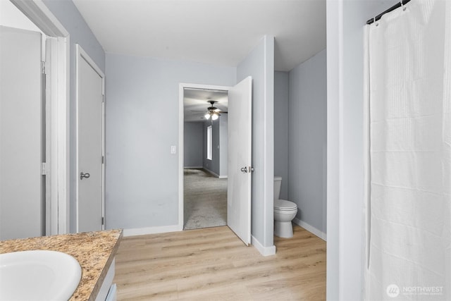 bathroom with baseboards, toilet, wood finished floors, and vanity