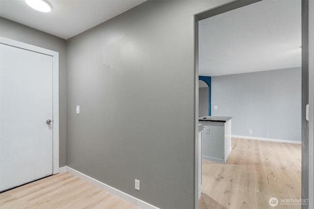 corridor featuring baseboards and light wood-type flooring