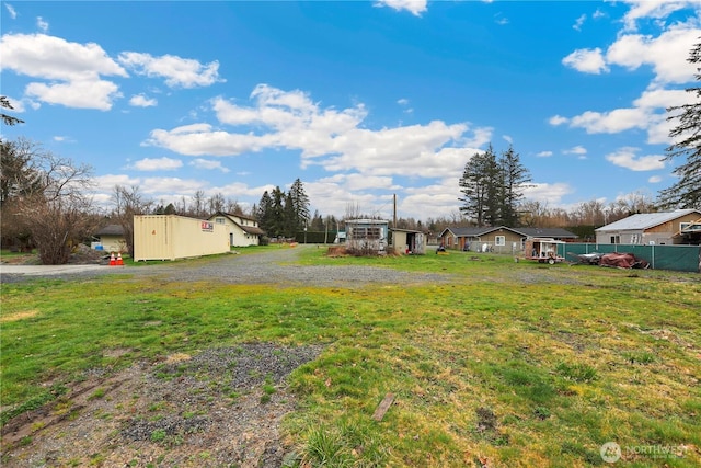 view of yard with driveway and fence